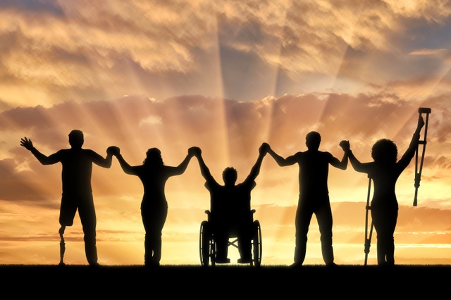 Group of people holding up hands with sunset in background