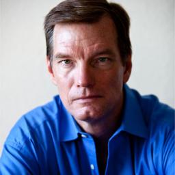 Image of John Quinn. He is wearing a blue shirt. His face has a determined look.